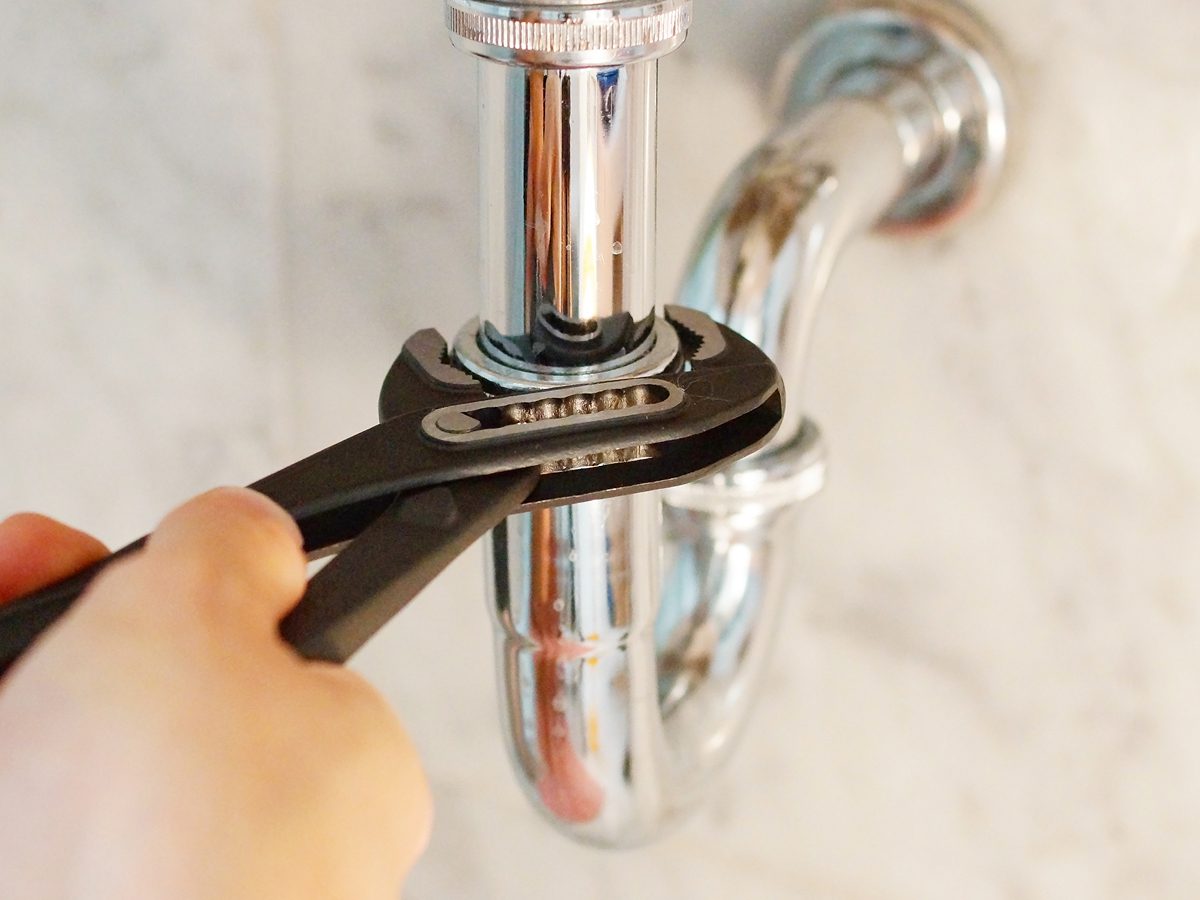 Plumber using wrench to repair plumbing
